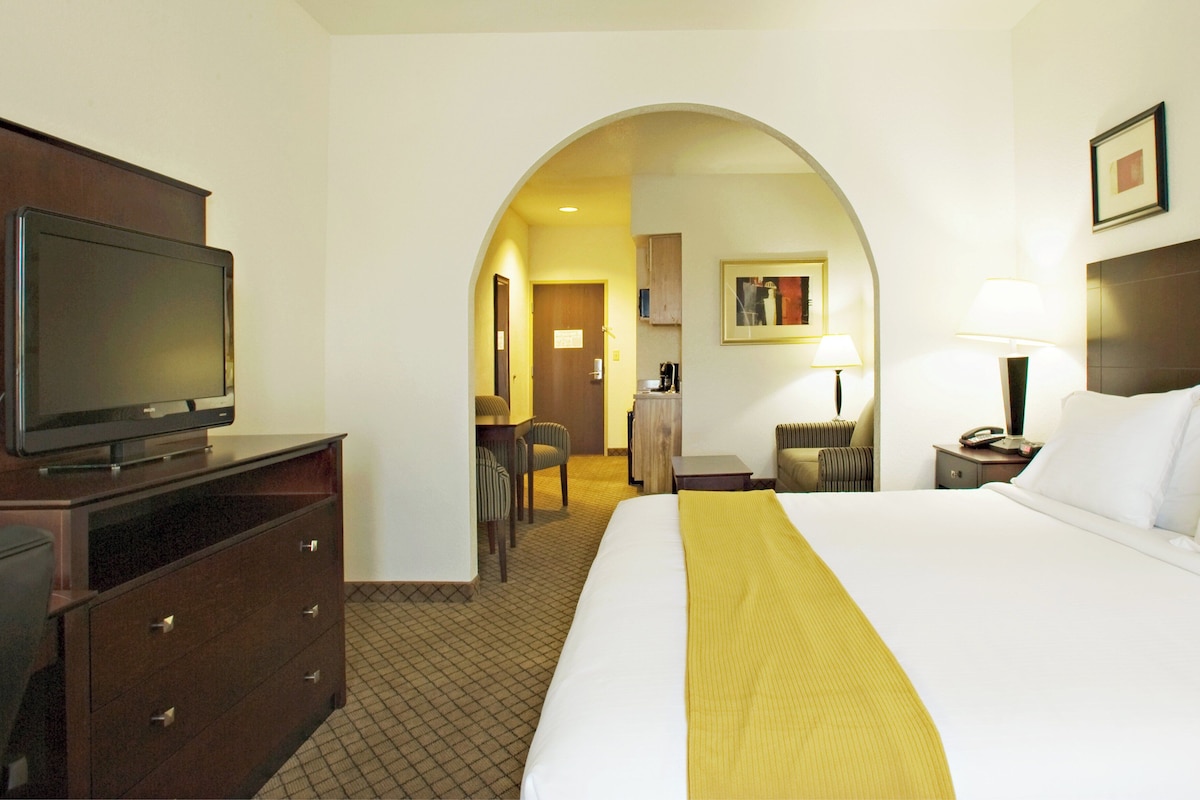 A hotel room with a bed, a television on a dresser, a desk, and a chair.