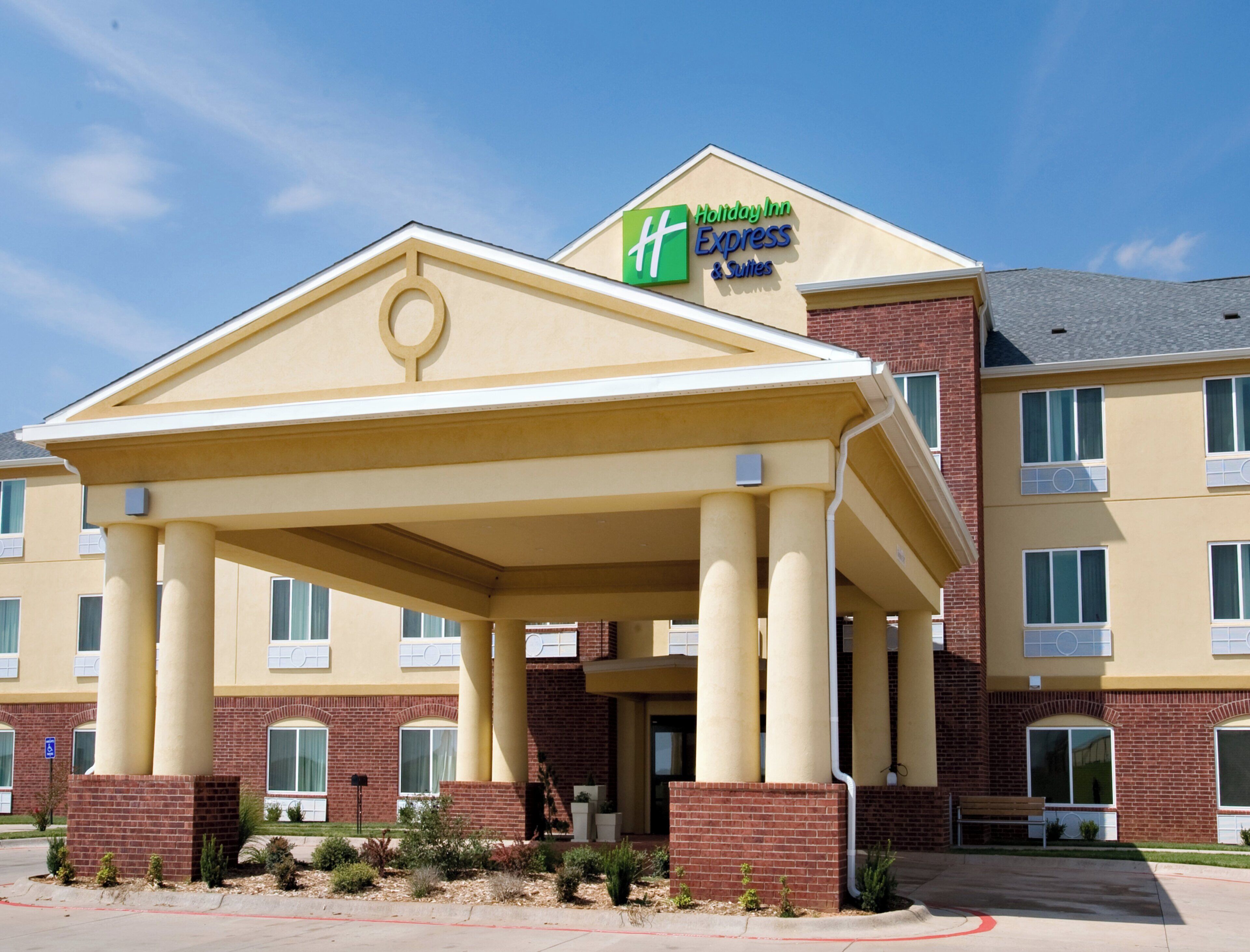 A Holiday Inn Express & Suites with a covered entrance, brick facade, and multiple windows.