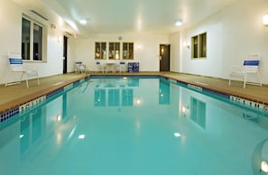 A swimming pool with a tiled edge, a clock on the wall, and a door with a window. - Holiday Inn Express & Suites Childress by IHG (Childress)