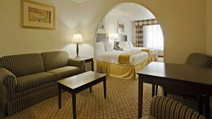 A hotel room with a sofa, a bed, a table, and a lamp.