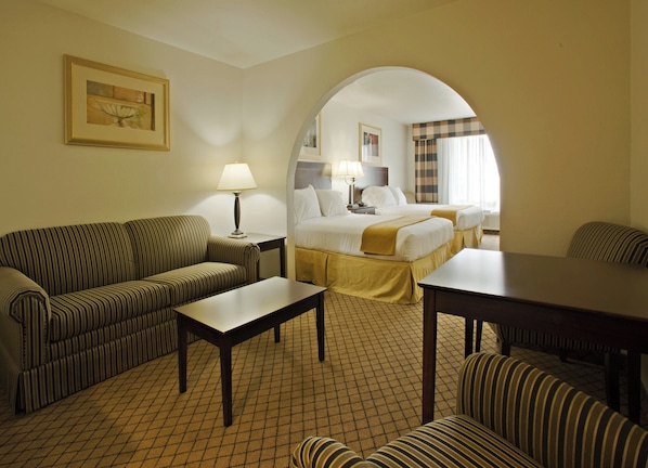A hotel room with a sofa, a bed, a table, and a lamp.