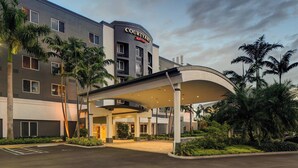 A Courtyard Marriott hotel with a covered entrance, palm trees, and a parking lot.
