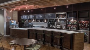 A bar area with a long counter, multiple seating options, and a menu board.