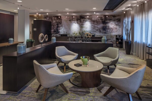 Un vestíbulo moderno con mostrador de recepción, zona de estar y una pared decorativa.