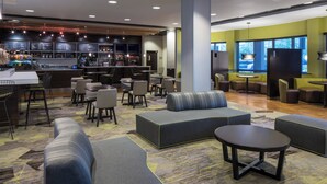 A modern lounge area with seating arrangements, a bar, and a menu display.