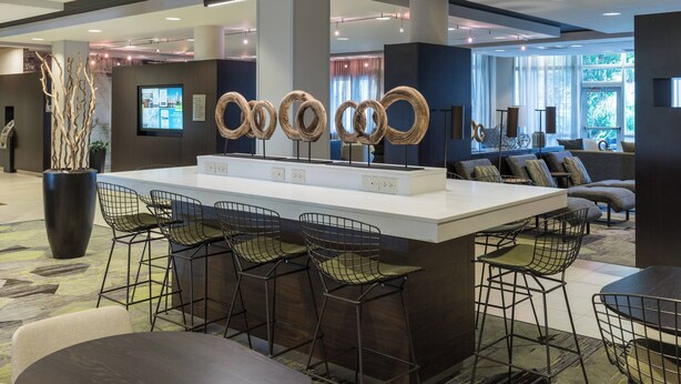 A modern bar area with a central island, bar stools, and a large potted plant.