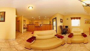 A living room with a sofa set, a desk with a computer, and a kitchen area in the background. - Econo Lodge Inn & Suites Rockmart (Rockmart)