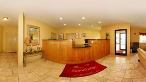 A reception area with a wooden reception desk, a large mirror, and a red carpet with the name 'Econo Lodge Rockmart, GA'. - Econo Lodge Inn & Suites Rockmart (Rockmart)