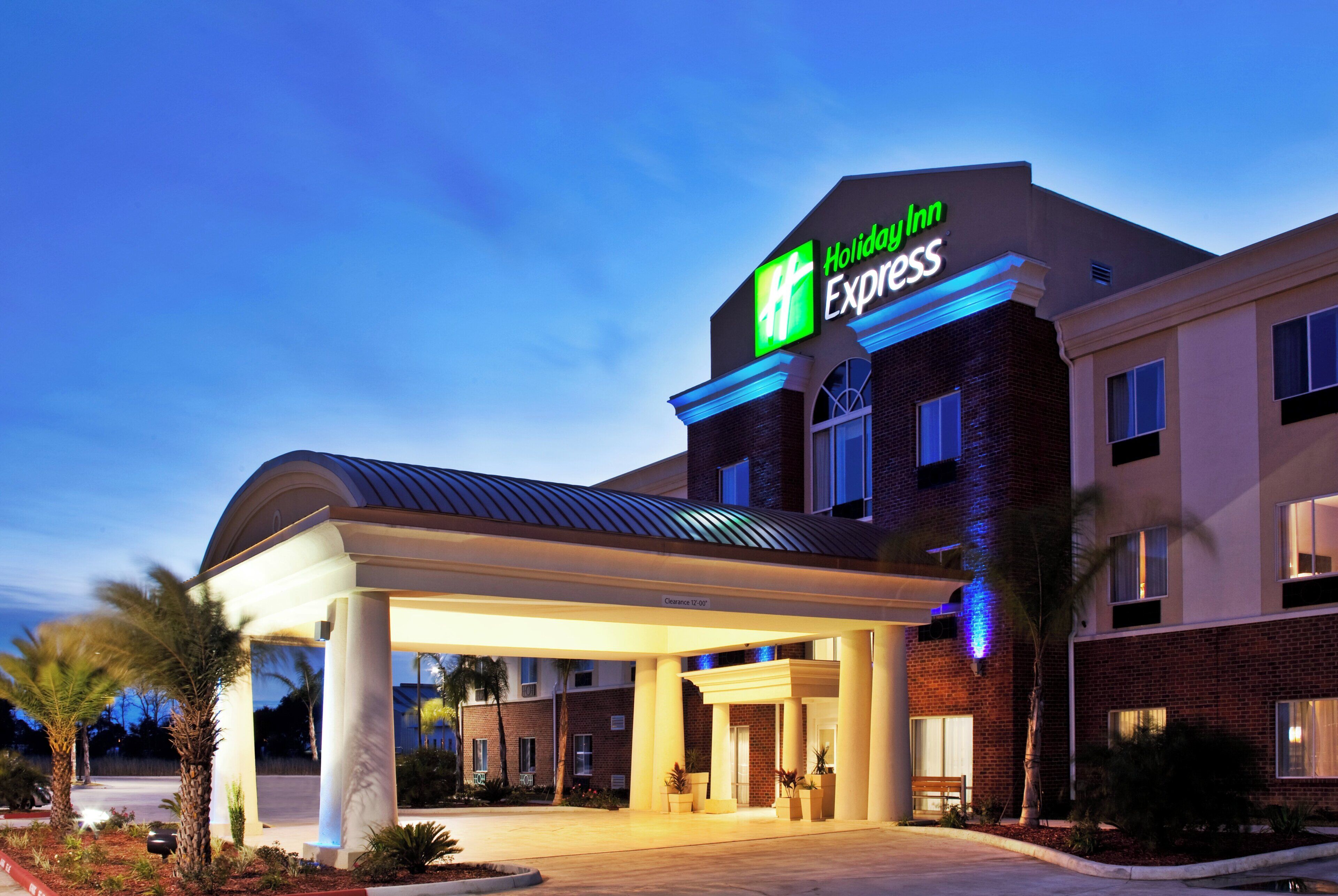 A Holiday Inn Express hotel with a covered entrance, brick facade, and a clear sky in the background.