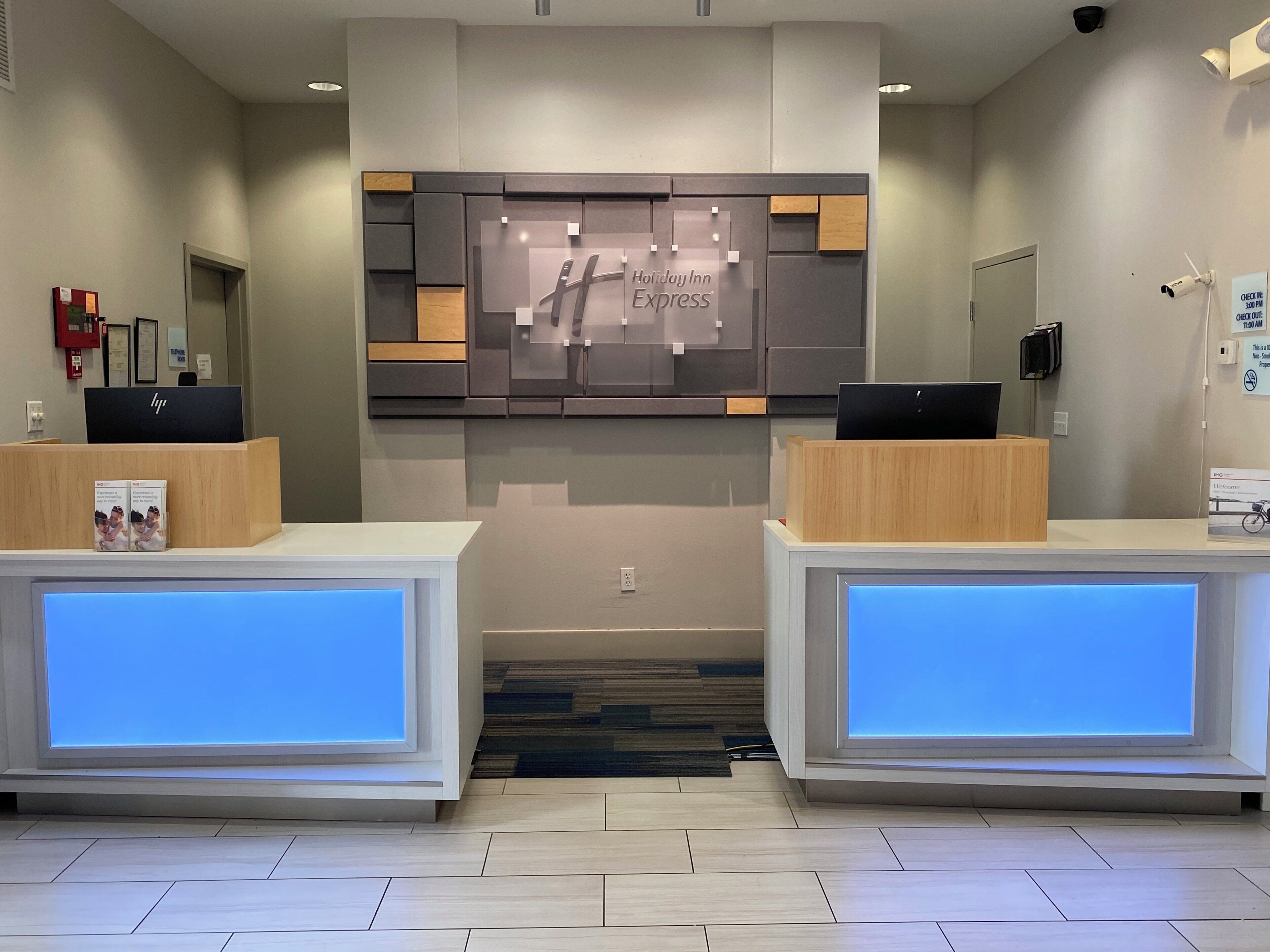 A hotel reception desk with a modern design, a digital display, and a sign for Holiday Inn Express.