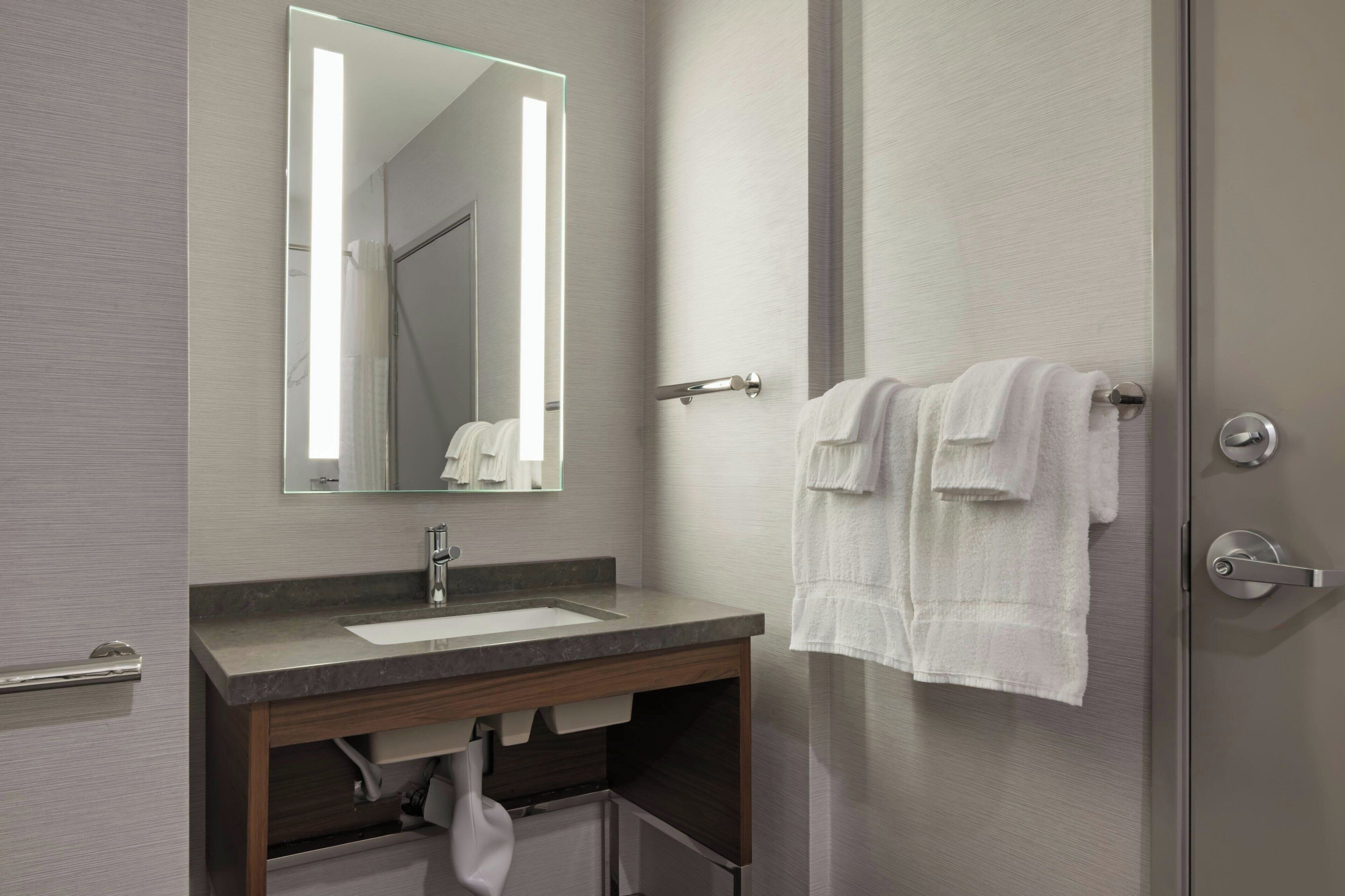 Ein modernes Badezimmer mit Waschbecken, Spiegel und Handtuchhalter.