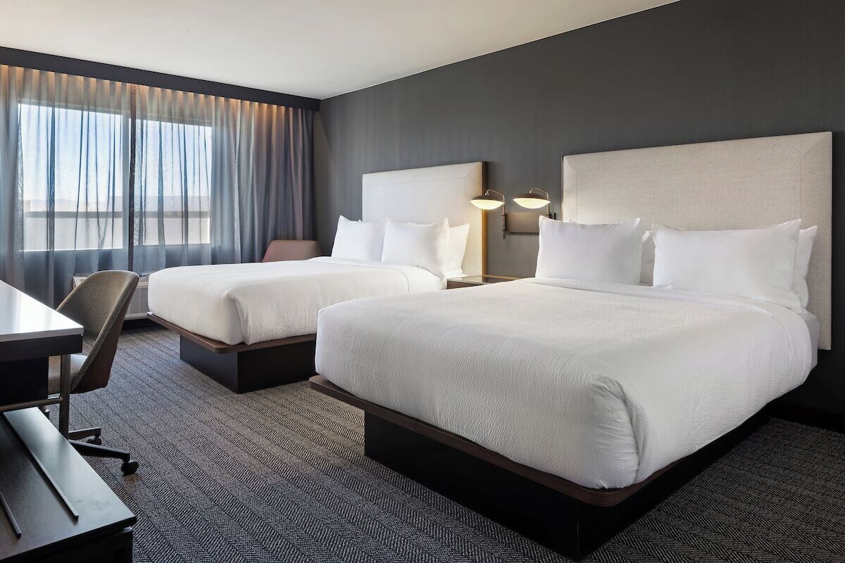 Une chambre d’hôtel avec deux lits, un bureau et une chaise.