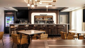 Un área de bar moderna con mostrador, asientos y una pantalla de televisión.