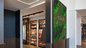 Un interior moderno con una barra de aperitivos llamada 'CRATE', que presenta una pared verde y estanterías de madera.