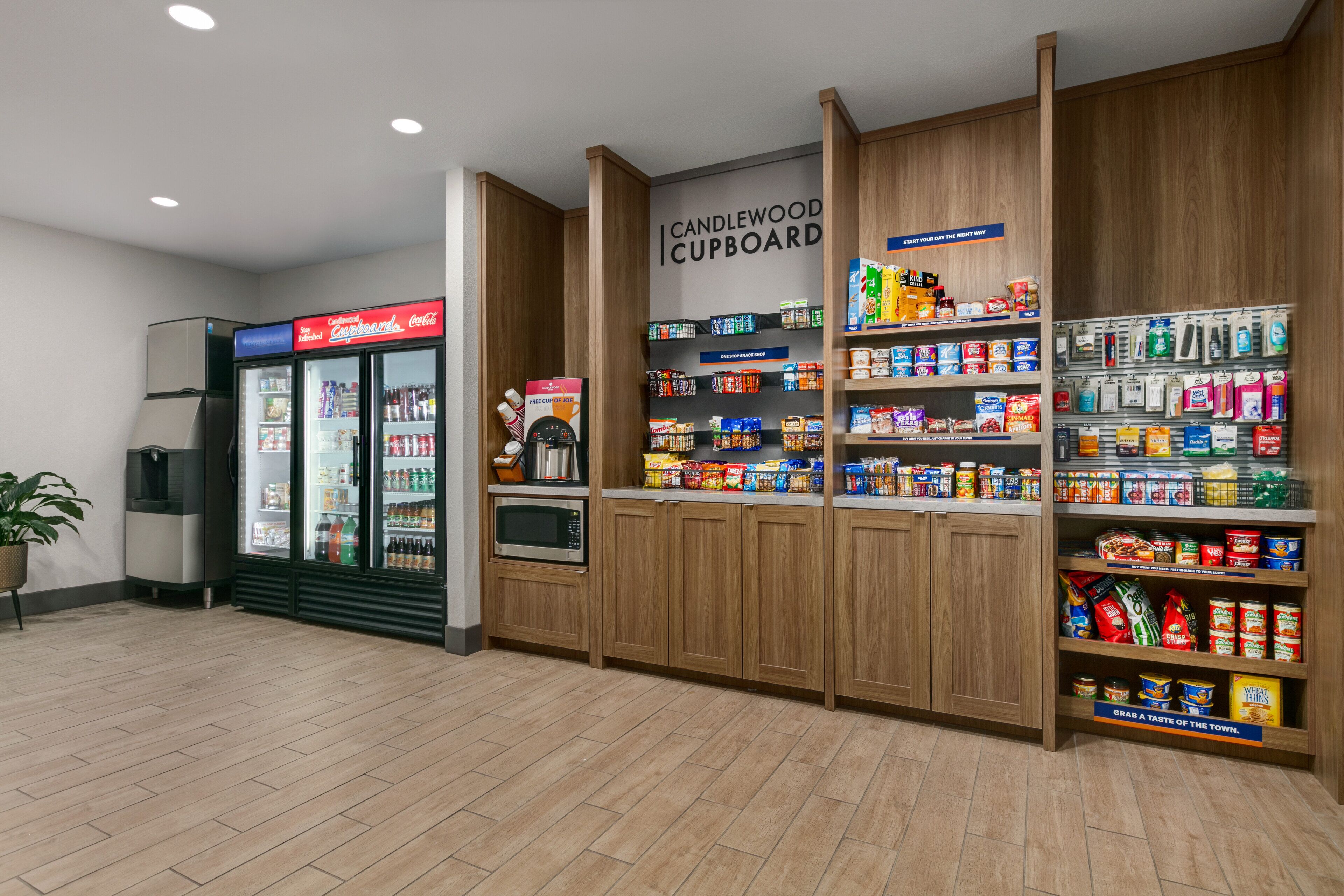 Eine Küchenzeile mit Kühlschrank, Mikrowelle und Regalen, die mit Snacks und Getränken gefüllt sind.