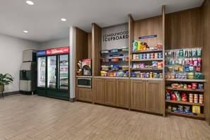 Eine Küchenzeile mit Kühlschrank, Mikrowelle und Regalen, die mit Snacks und Getränken gefüllt sind.