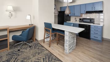 Een moderne keuken met blauwe kastjes, een wit eiland en een eetgedeelte met blauwe stoelen.