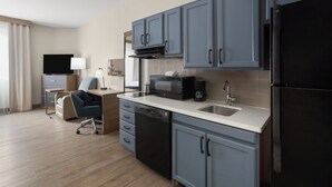 Una cocina moderna con armarios grises, un refrigerador negro, un microondas y una cafetera.
