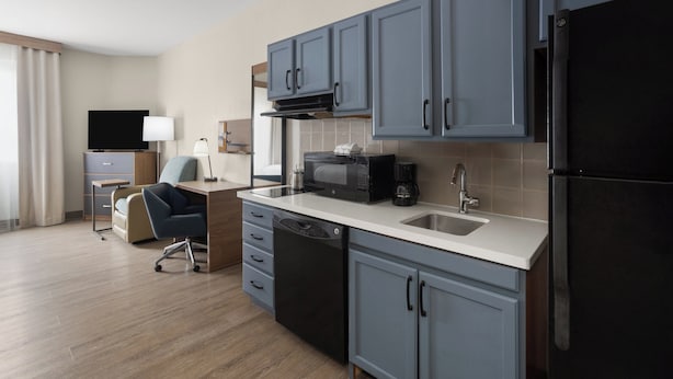 A modern kitchen with grey cabinets, a black refrigerator, a microwave, and a coffee maker.
