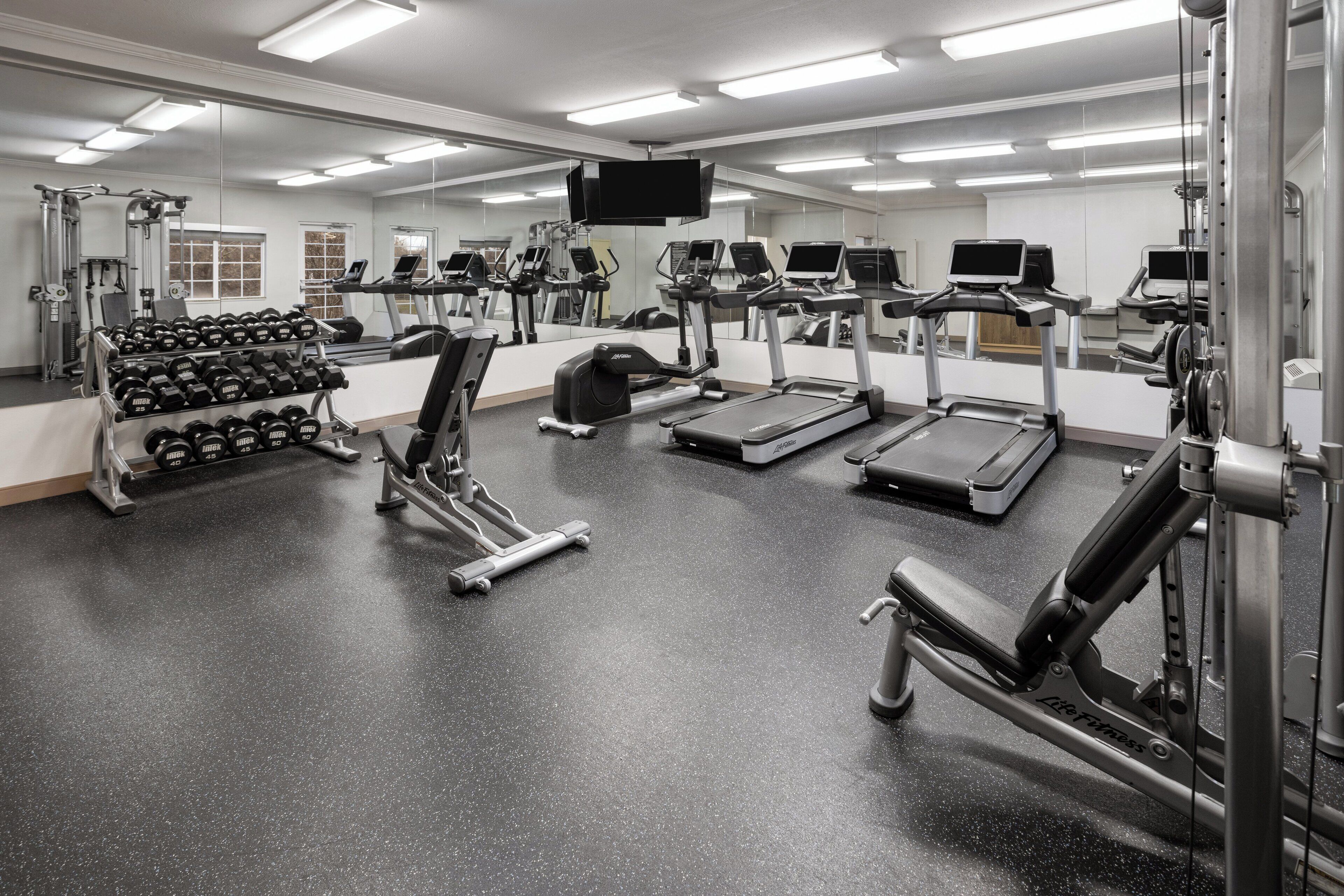 A gym with treadmills, weight machines, and dumbbells.