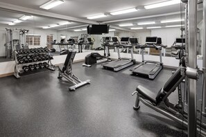 Ein Fitnessstudio mit Laufbändern, Kraftgeräten und Kurzhanteln.