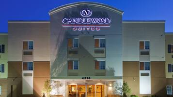 Un hotel con un llamativo letrero de 'CANDLEWOOD SUITES', una entrada a nivel de suelo y el número '4216' visible.