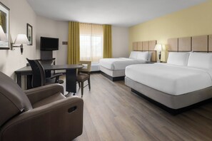 Ein Hotelzimmer mit Schreibtisch, zwei Betten, Fernseher und Stuhl.