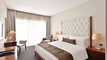 A hotel room with a large bed, a desk, a chair, and a TV.