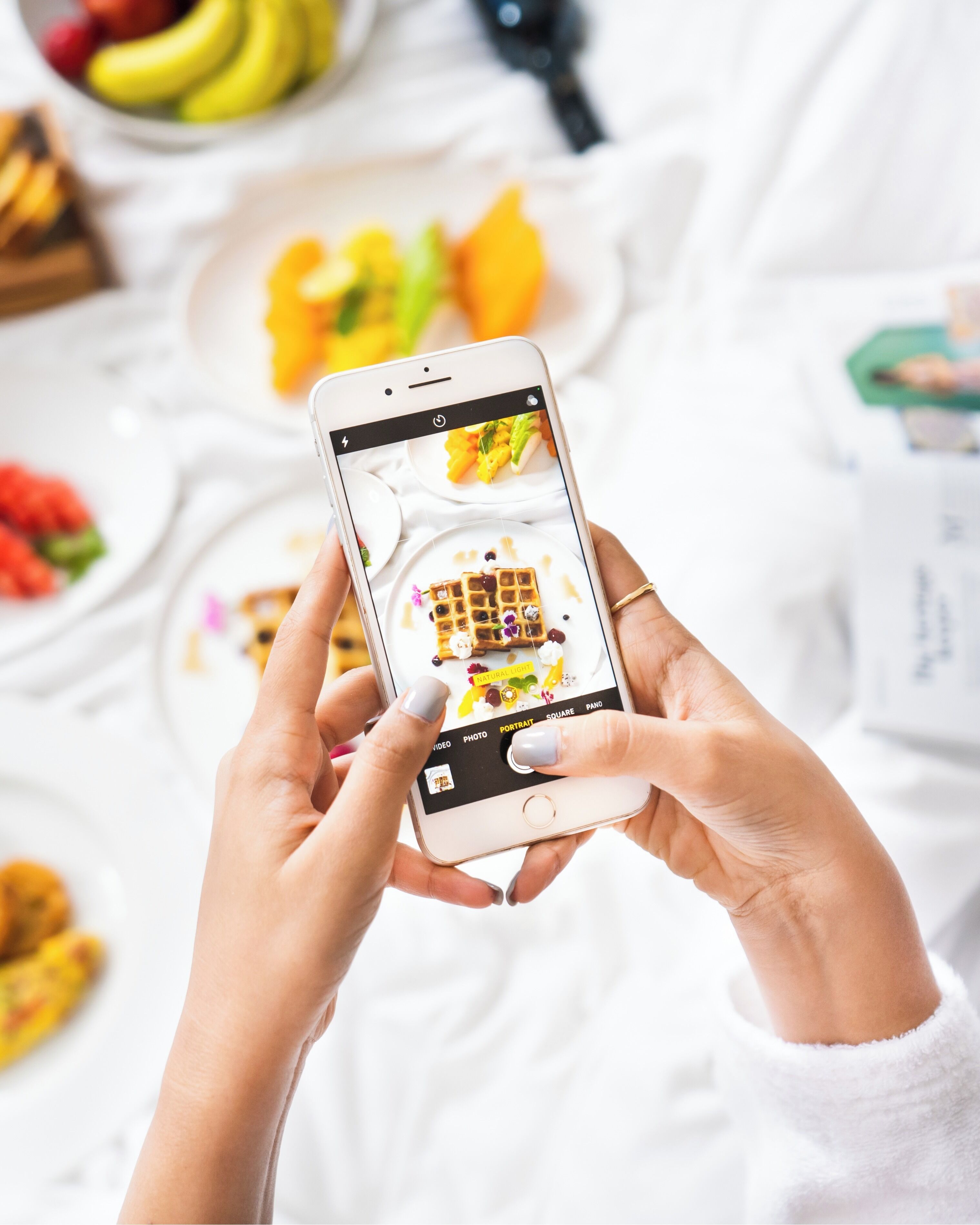 Eine Person hält ein Smartphone mit einer geöffneten Foto-Bearbeitungs-App, auf der ein Foto von Essen zu sehen ist.