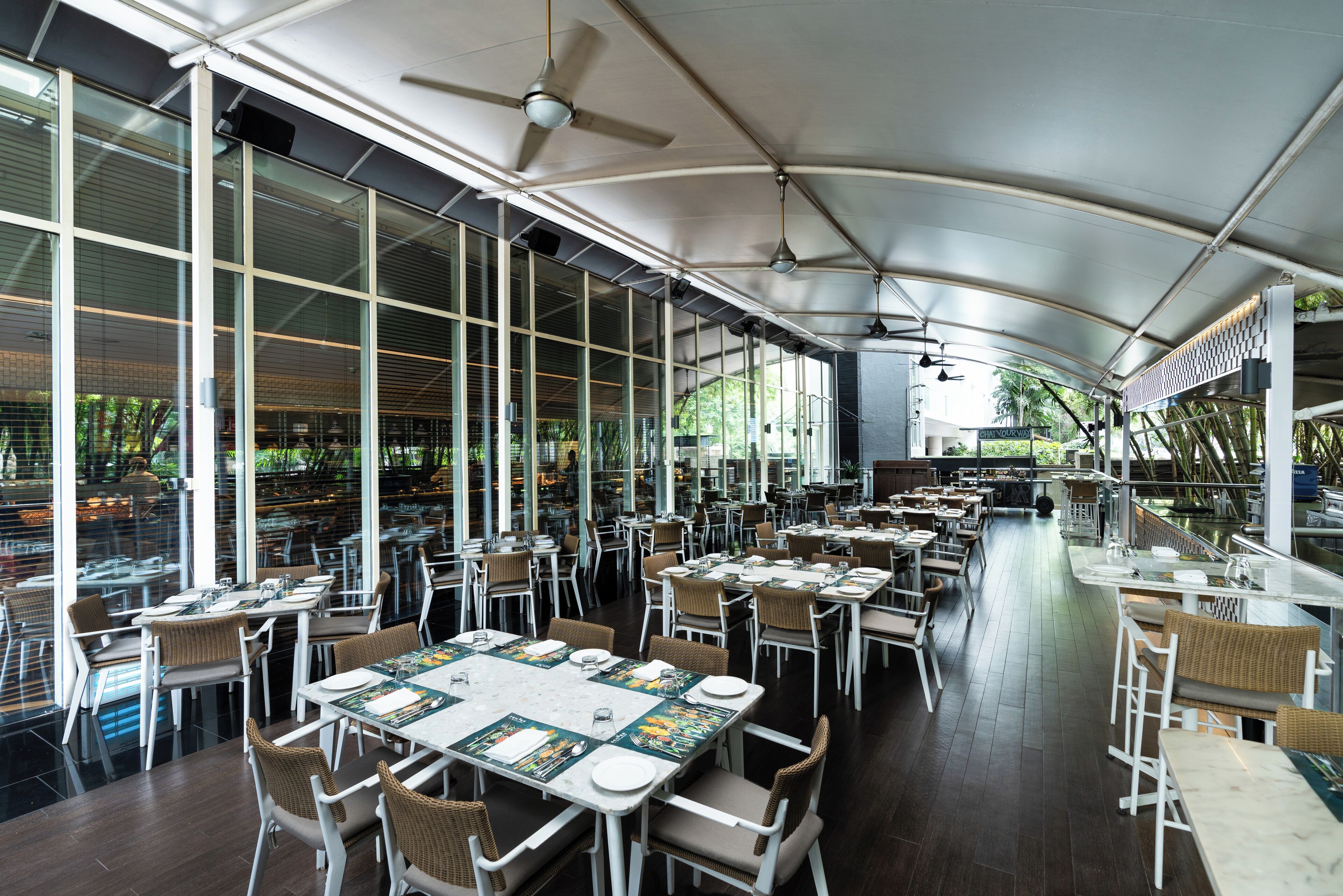 A spacious restaurant with high ceilings, large windows, and a variety of seating arrangements.