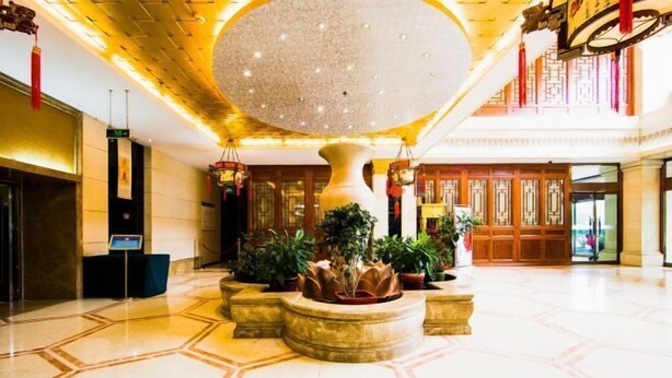 A spacious lobby with a large central column, potted plants, and traditional decor. - Beijing Bao Lin Xuan International Hotel (Beijing)