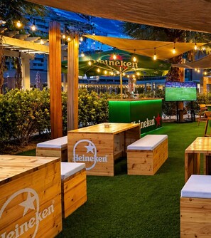 An outdoor seating area with wooden benches and a green table branded with Heineken.