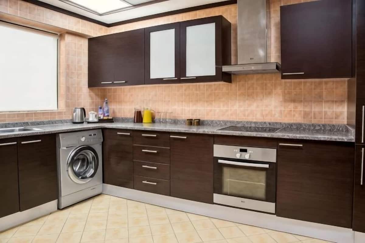 A kitchen with dark cabinets, a washing machine, and a built-in oven.