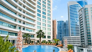 A modern hotel with a swimming pool, sun loungers, and a swan statue. - TIME Oak Hotel & Suites (Dubai)