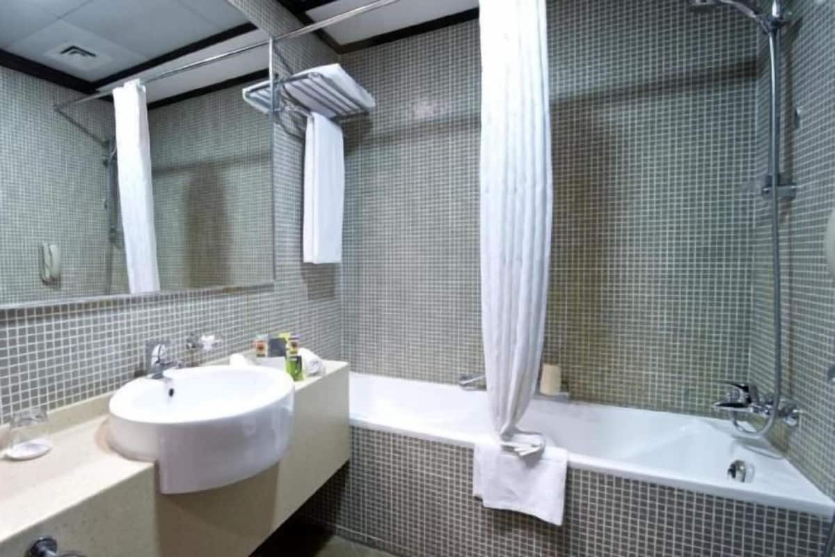 A bathroom with a sink, mirror, shower, and tiled walls.