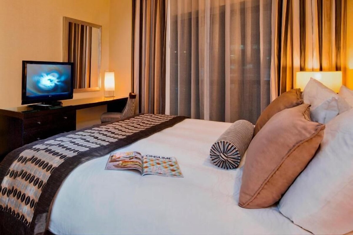 A hotel room with a bed, a television, a desk, and curtains.