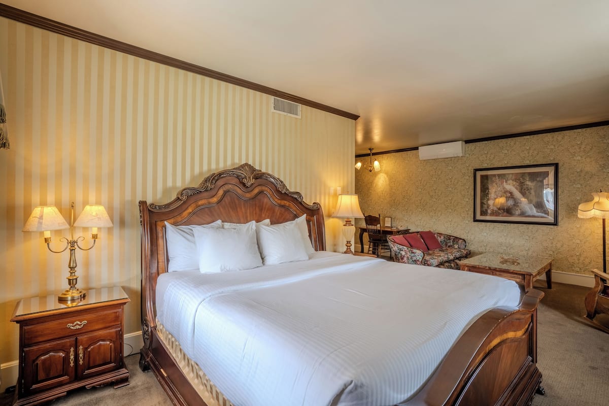 A hotel room with a large bed, two bedside tables with lamps, a chair, and a painting on the wall.