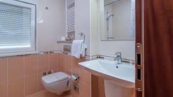 Un baño con inodoro, lavamanos y ducha.