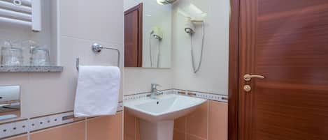 A bathroom with a sink, mirror, towel rack, and a wooden door.