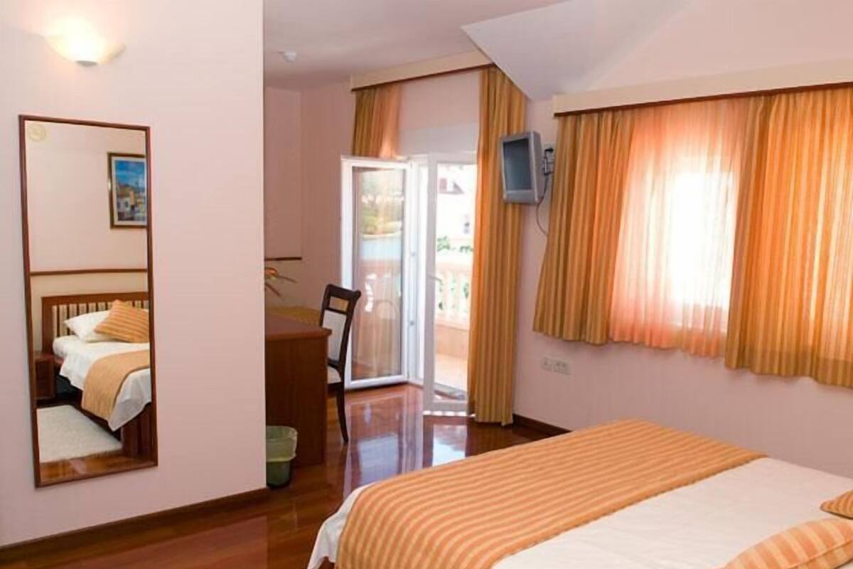A bedroom with a bed, a chair, a television, and a sliding glass door leading to an outdoor area.