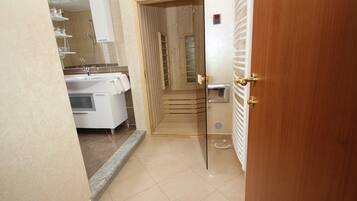 A hotel bathroom with a shower, a sink, and a mirror.
