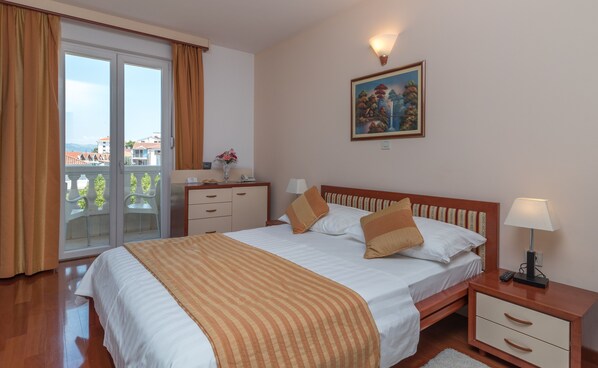 A hotel room with a bed, a desk, a chair, a nightstand, a lamp, and a painting on the wall. - Hotel Trogir Palace (Trogir)