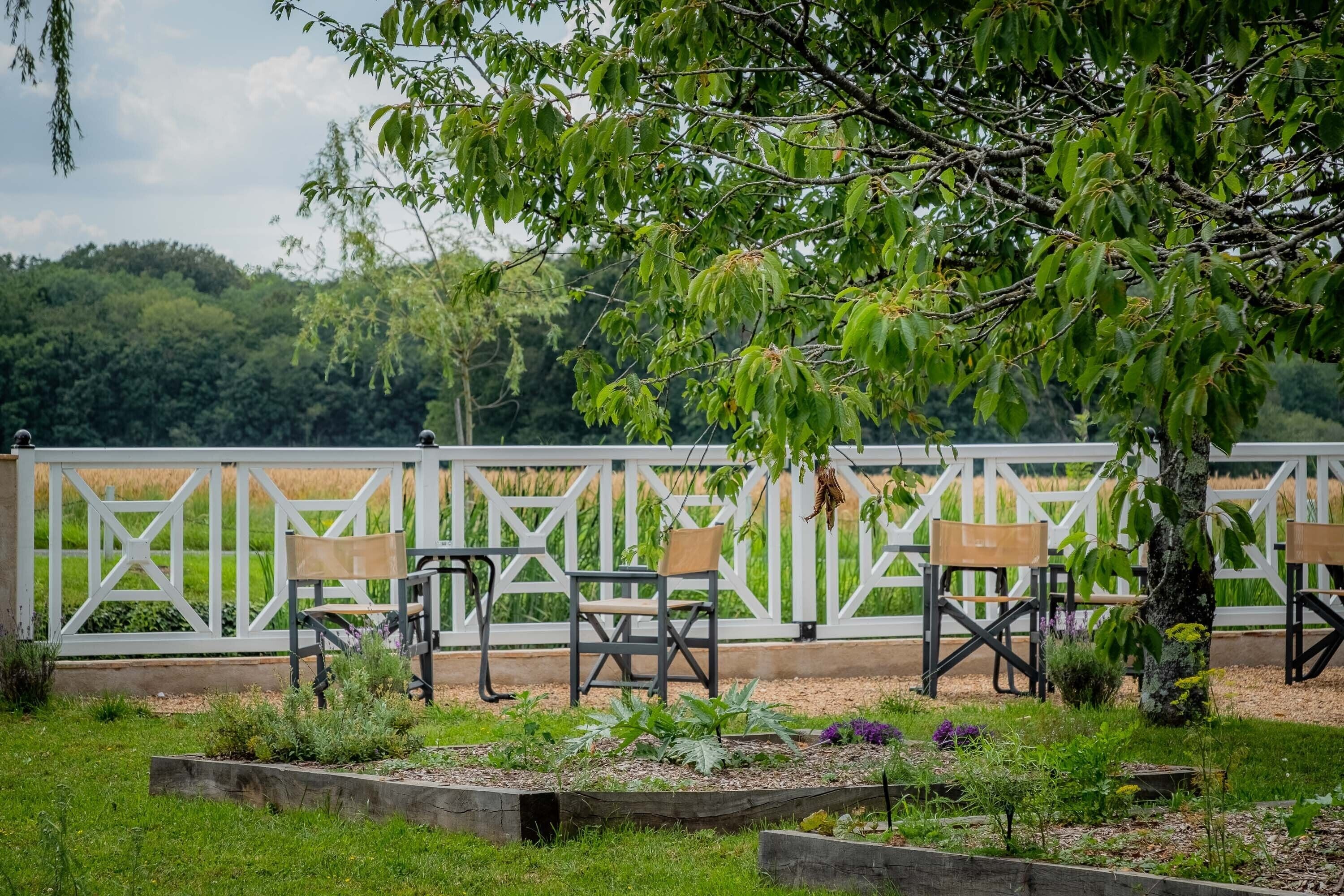 Un jardin avec des chaises en bois et une clôture blanche.