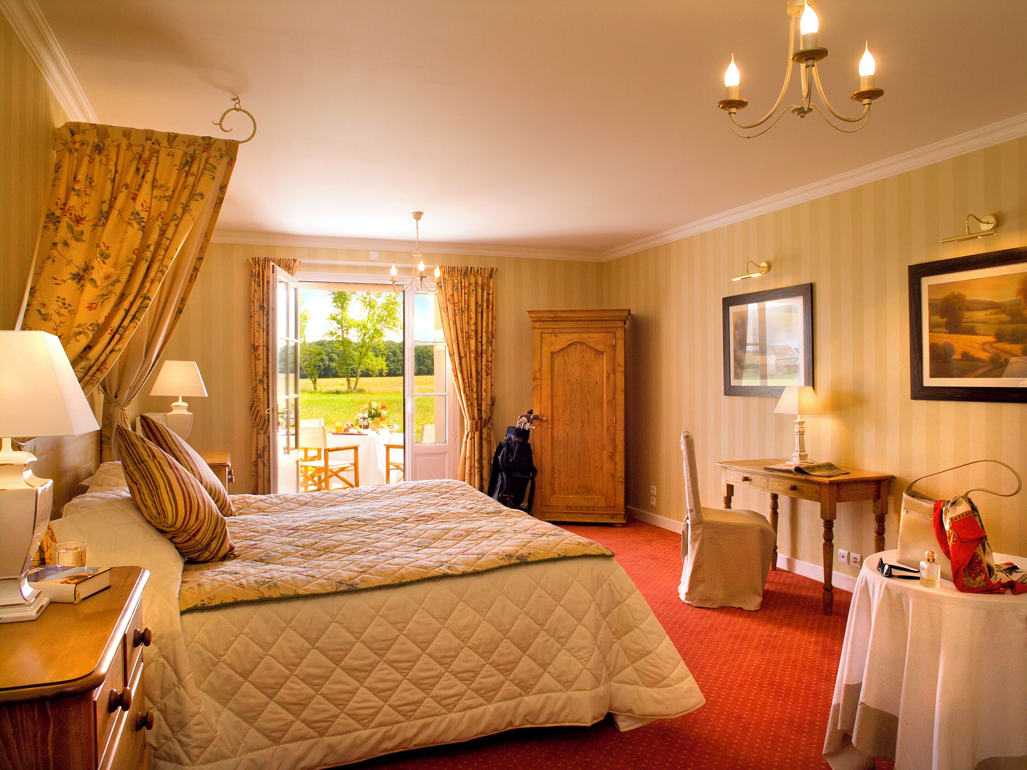 A hotel room with a bed, a desk, a chair, a wardrobe, and a view of the outdoors.
