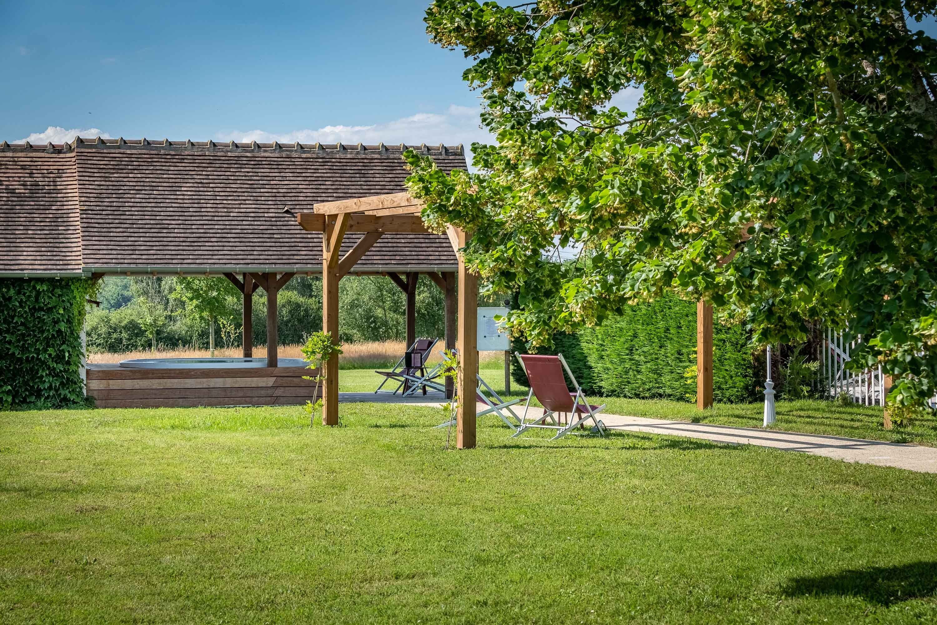 A gazebo with a tiled roof, surrounded by a well-maintained lawn and trees.