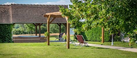 A gazebo with a tiled roof, surrounded by a well-maintained lawn and trees.