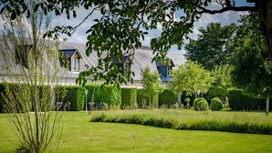 Uma casa com um jardim bem cuidado, gramado e sebes.