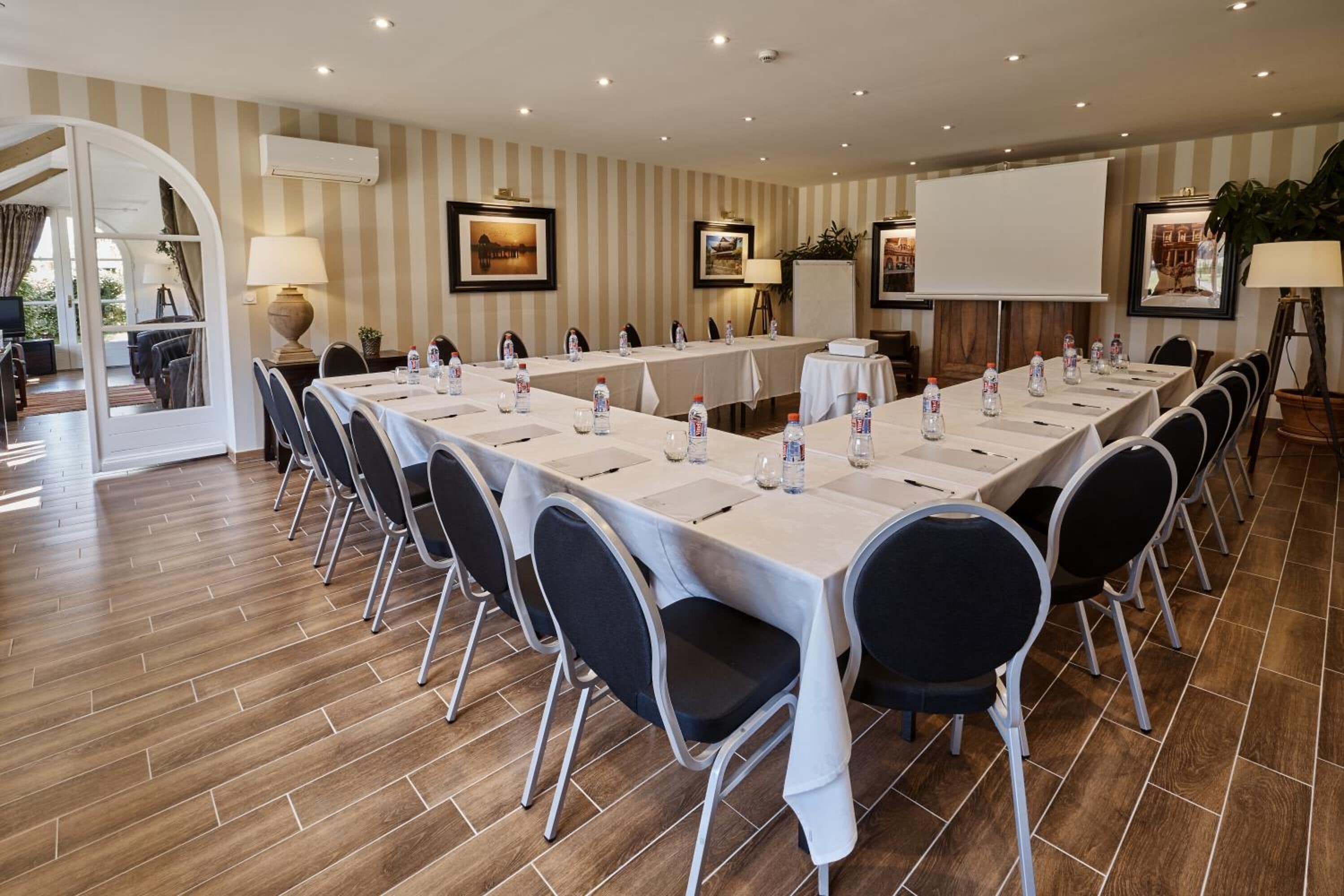 A conference room with a long table, chairs, and a projector screen.