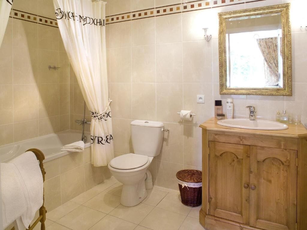 A bathroom with a bathtub, toilet, and wooden vanity.