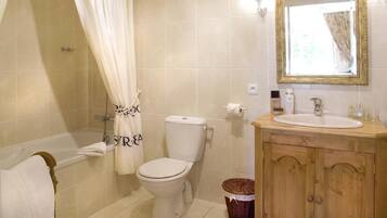 A bathroom with a bathtub, toilet, and wooden vanity.